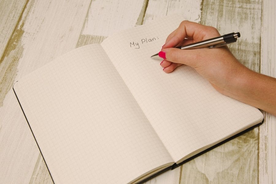 Person writing a plan in a notebook to show moving companies in Lewisville