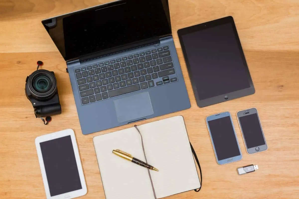 Laptop, phones, and camera on a desk